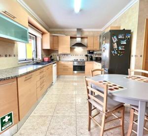 a large kitchen with a table and a refrigerator at La villa du Paradis du Coto - Piscine-Mer&Surf in Coto