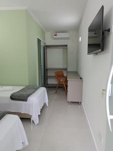 Pokój z 2 łóżkami, telewizorem i krzesłem w obiekcie Pousada Emcontrei w mieście São João da Barra