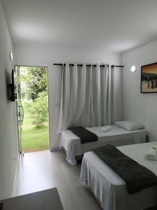 sypialnia z 2 łóżkami i przesuwnymi szklanymi drzwiami w obiekcie Pousada Emcontrei w mieście São João da Barra