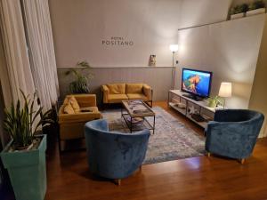 a living room with two blue chairs and a television at Hotel Positano in Bassano del Grappa