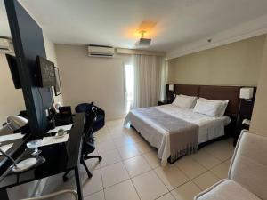Habitación de hotel con cama y TV en Flat com Vista Deslumbrante na Praia do Pecado en Macaé