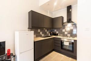 uma cozinha com armários pretos e um frigorífico branco em Stunning Ground Floor flat in Southside. em Glasgow