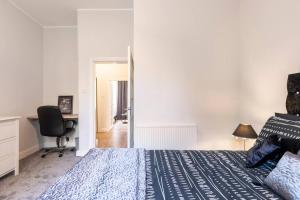 um quarto com uma cama, uma secretária e uma cadeira em Stunning Ground Floor flat in Southside. em Glasgow