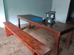 une table en bois avec un banc et un vase. dans l'établissement Casona el ancla, à Eldorado