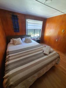 1 dormitorio con 1 cama grande y paredes de madera en Hostal Isla Mágica en Castro