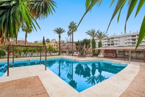 uma piscina com palmeiras e um edifício em Piso con 2 habitaciones, 2 terrazas y piscina em Torremolinos