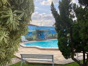 CONFORT HOTEL ARAPIRACA في أرابيراكا: حمام سباحة مع مقعد أمام الجدار