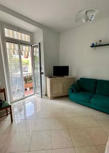 salon z zieloną kanapą i telewizorem w obiekcie Baia Lunare w mieście Vado Ligure
