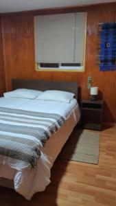a bedroom with a bed with a window and a wooden floor at Hostal Isla Mágica in Castro