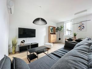ein Wohnzimmer mit einem Sofa und einem TV in der Unterkunft [PARENTHESE] Le ChiFouMi - 6pers in Saint-Jory