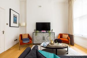 ein Wohnzimmer mit einem blauen Sofa und orangefarbenen Stühlen in der Unterkunft Marylebone Luxury 2 Bed Appartment in London