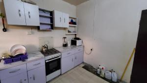 uma pequena cozinha com fogão e armários brancos em Weltons Apartments em Ikeja