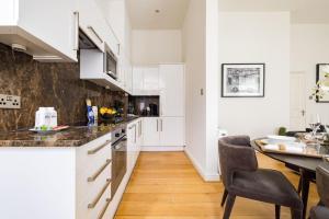 a kitchen with white cabinets and a table and chairs at Marylebone Luxury 2 Bed Appartment in London