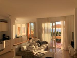 Vivienda Atlantico في تازاكورتي: غرفة معيشة مع أريكة بيضاء ومطبخ