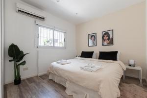 Un dormitorio blanco con una cama grande con toallas. en Fliphaus Salvador 6000 - 2 Bd Duplex Palermo en Buenos Aires