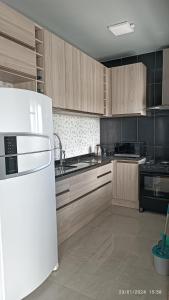 a kitchen with wooden cabinets and a white refrigerator at Sobrado Completo Belíssima in Pelotas