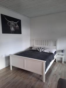 a white bedroom with a bed with a black blanket at Ferienwohnung K1 in Hambühren