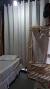 a bedroom with a bed and a white curtain at Caiowa Floripa guesthouse in Florianópolis