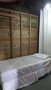 a bed with a wooden headboard in a room at Caiowa Floripa guesthouse in Florianópolis