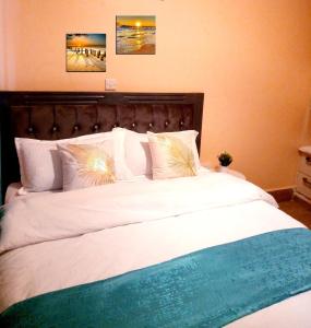 a large bed with white sheets and pillows at T-Tree Paradise Apartments in Embu