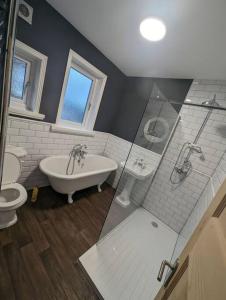 a bathroom with a tub and a toilet and a sink at 3 bed home, pool-hot tub & ev charger in Darlington