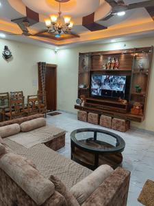 uma sala de estar com sofás e uma televisão de ecrã plano em Adbhut Nivas (Home Stay) em Bhopal