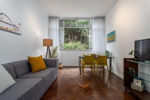 uma sala de estar com um sofá e uma mesa em 2 Quartos - Amplo e confortável perto do Metro Flamengo no Rio de Janeiro
