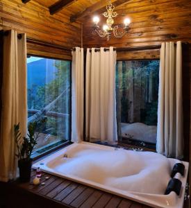 een bad in een kamer met een groot raam bij Alto da colina Caraá RS in Caraá