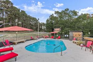 a swimming pool with red chairs and a table at Stonegate Lodge Saltwater Pool 2 Queen Beds Firepit Fast WiFi Room #307 in Eureka Springs