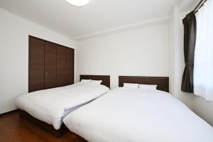 Pleasure Maruyama - Vacation STAY 52780v في سابورو: سريرين في غرفة نوم مع ملاءات بيضاء ومناديل خشبية