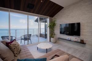 una sala de estar con sofá y TV y el océano en La-se-ri Resort & Stay - Vacation STAY 63385v, en Himi