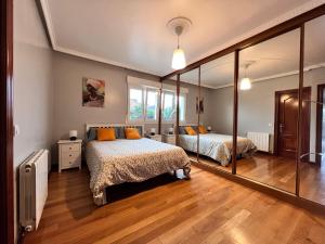 een slaapkamer met 2 bedden en een grote spiegel bij Villa Senda costera. Un lugar natural en la ciudad in Santander