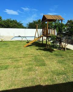 un parco giochi in legno in un cortile accanto a una piscina di Chalé Brisa das Fontes a Beberibe
