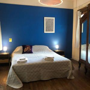 1 dormitorio azul con 1 cama con 2 toallas en Apartamento de estilo en edificio patrimonial en Montevideo