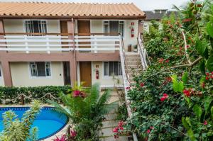 a villa with a swimming pool in front of a house at Pousada Vila da Praia in Bertioga