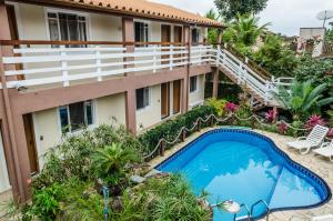 um apartamento com uma piscina em frente a um edifício em Pousada Vila da Praia em Bertioga