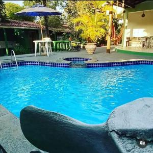 a large blue swimming pool with a table and an umbrella at Casa Clorophila in Vila Velha