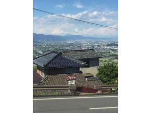 a building on a hill with a view of a city at Obasute Guesthouse Nakaraya - Vacation STAY 31596v in Chikuma