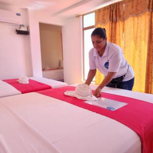 a woman is putting a hat on a bed at La Casa De Mi Sub in Puerto Baquerizo Moreno