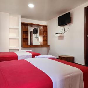 2 camas en una habitación con TV en la pared en La Casa De Mi Sub en Puerto Baquerizo Moreno