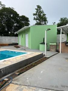 a green building with a swimming pool in a yard at Pousada Encanto das águas in Águas de São Pedro