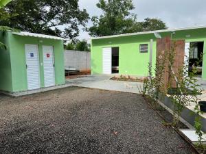 a green house with white doors and a driveway at Pousada Encanto das águas in Águas de São Pedro