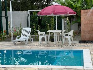 a table and chairs with an umbrella next to a pool at Pousada Encanto das águas in Águas de São Pedro
