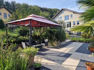 a pavilion with a red umbrella in a garden at Weingut im Moselkrampen in Ellenz-Poltersdorf