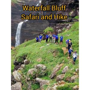 a group of people walking on a hill with a waterfall at Louis at Magwa Falls in Lusikisiki