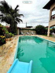 a swimming pool in a yard with chairs and a house at Pousada Casa Chico in Navegantes