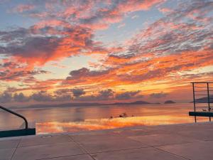 un coucher de soleil sur une masse d'eau avec un banc dans l'établissement Mark Heritage, à Glossa