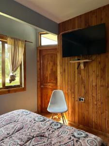 een slaapkamer met een bed en een flatscreen-tv bij QUELEN PATAGONIA in Villa Cerro Castillo