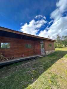 a log cabin with a porch on a grass field at QUELEN PATAGONIA in Villa Cerro Castillo