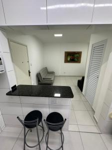 a kitchen with two chairs and a counter in a room at Kitnet em frente a praia de Santos in Santos